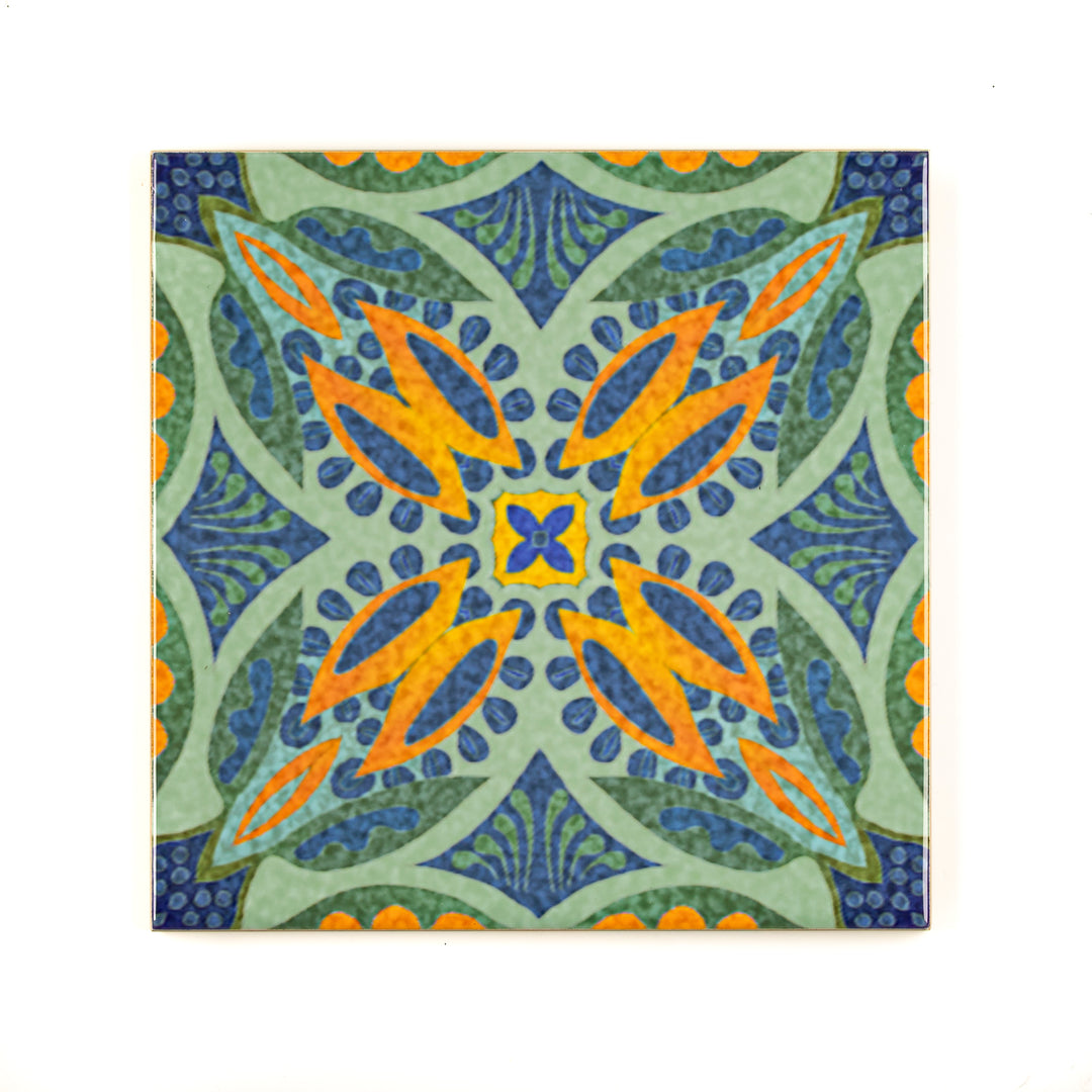 A ceramic wall tile with a geometric pattern featuring a soft sage green with dark blue flourishes and an orange flower center.