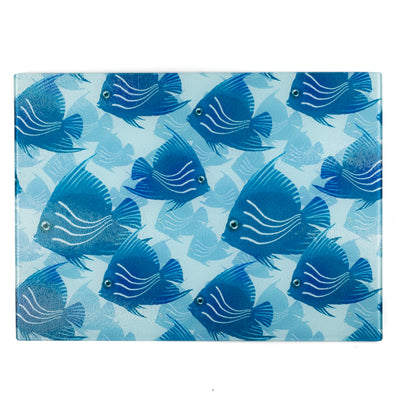 A rectangular glass cutting board with a pattern of hand-drawn blue and turquoise angel fish on a blue grey sea background.