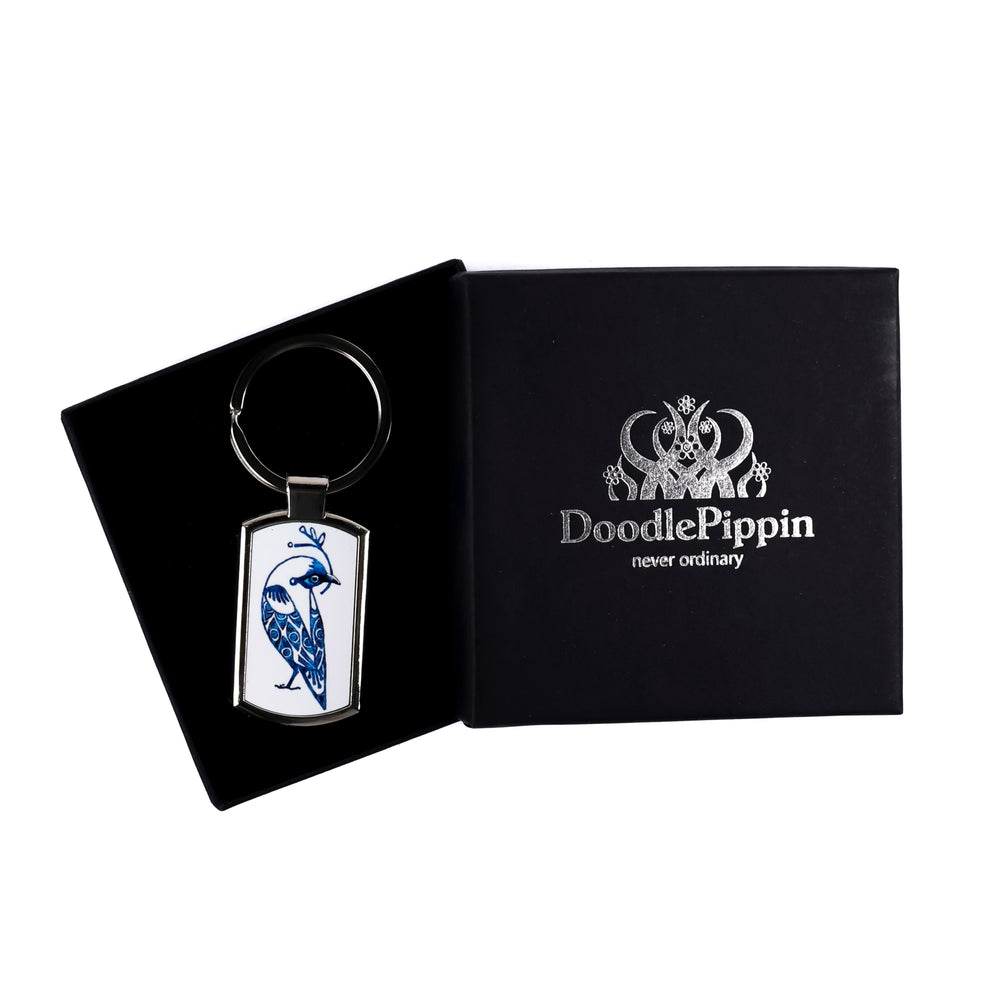 A metal keyring with a blue and white millefiori print inlay, in a black DoodlePippin box with velvet liner.